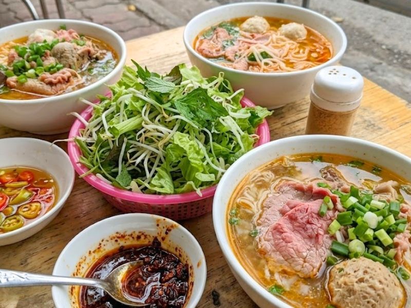 Bun bo Hue with beef shank, pork hock, thick rice noodles, lemongrass broth, chili, and fermented shrimp paste