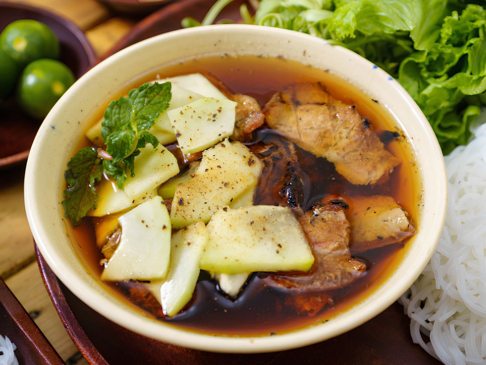 bun cha Hanoi spread with grilled pork in warm dipping sauce, noodles, and a herb plate