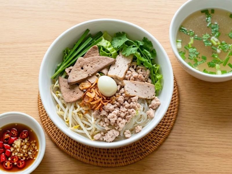Hu tieu Nam Vang with clear pork broth, noodles, shrimp, pork, quail eggs, and fresh toppings