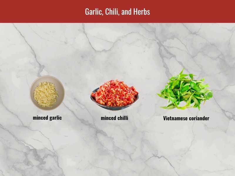 Nem chua aromatics including garlic, bird's eye chili, Vietnamese coriander, and wrapping herbs