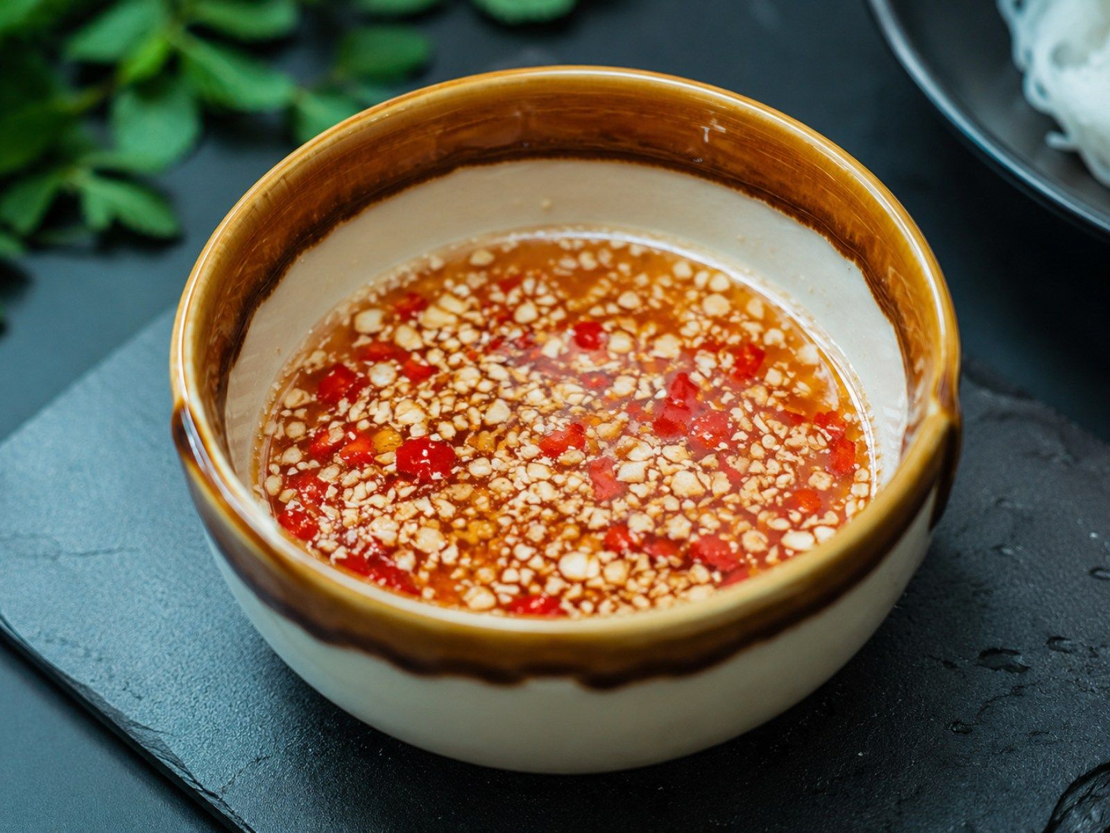 Nuoc cham served in a dipping bowl alongside Vietnamese dishes such as spring rolls and grilled meat