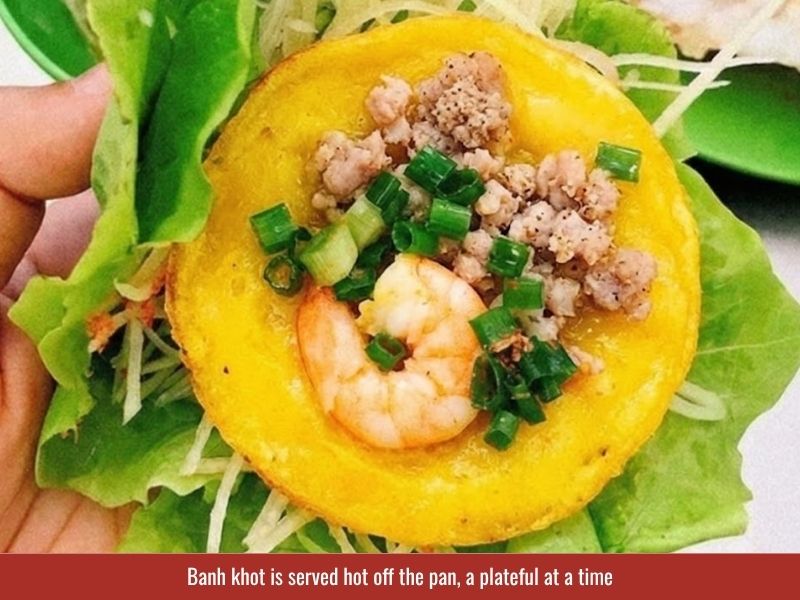Serving banh khot with lettuce, fresh herbs, vegetables, and Vietnamese fish sauce dipping sauce
