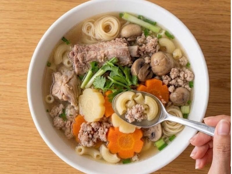 Serving Vietnamese sup nui with pork ribs, macaroni, herbs, fried shallots, and fresh seasonings