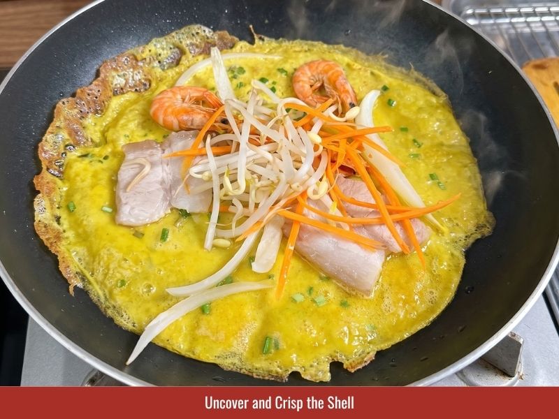 Cooking banh xeo uncovered until the edges become golden and crispy