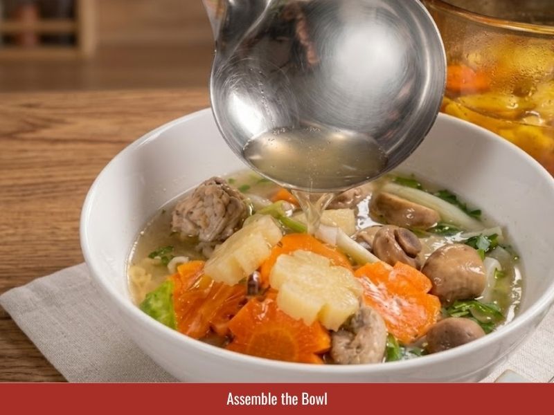 Assembling sup nui bowl with macaroni, pork ribs, ground pork, vegetables, broth, and toppings