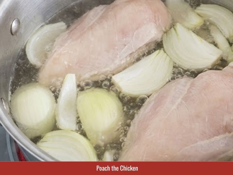 Poaching chicken breast with onion and salt to prepare the broth base for sup mang cua