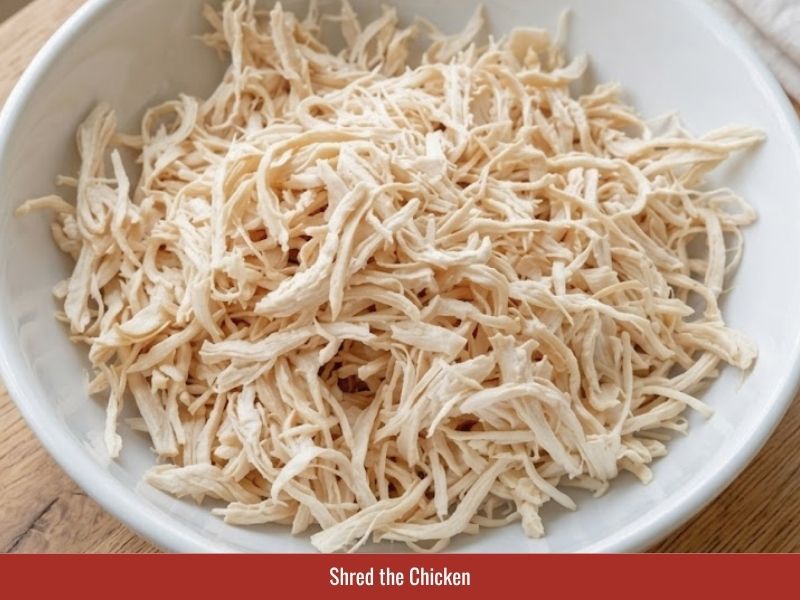 Shredding cooked chicken into thin strands for Vietnamese sup mang cua
