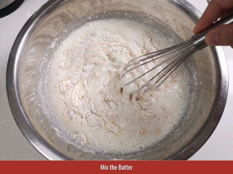 Mixing banh xeo batter with rice flour, coconut milk, sparkling water, turmeric, and green onion
