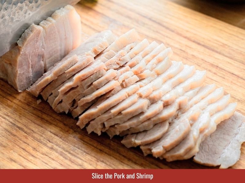 Slicing pork belly and halving shrimp lengthwise for easier Vietnamese spring roll assembly