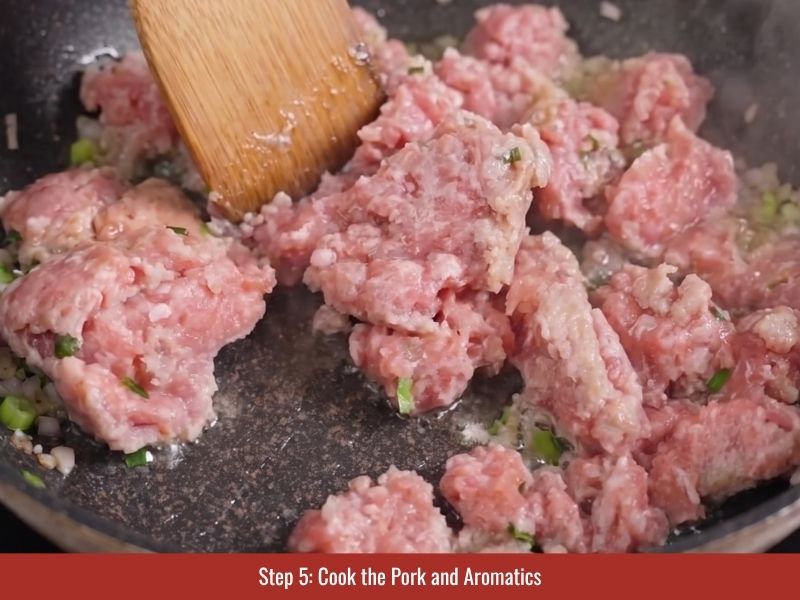 Cooking minced pork with shallots and scallions to prepare the savory banh cuon filling