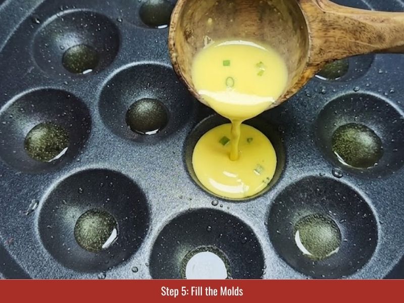 Pouring banh khot batter into hot molds and adding shrimp and pork toppings
