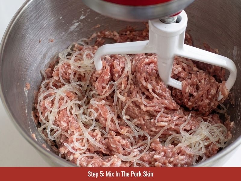 Adding sliced pork skin strands into the fermented meat mixture for nem chua texture