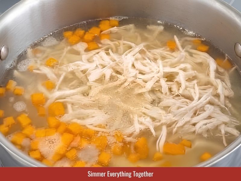 Simmering Vietnamese crab and asparagus soup until ingredients are heated through