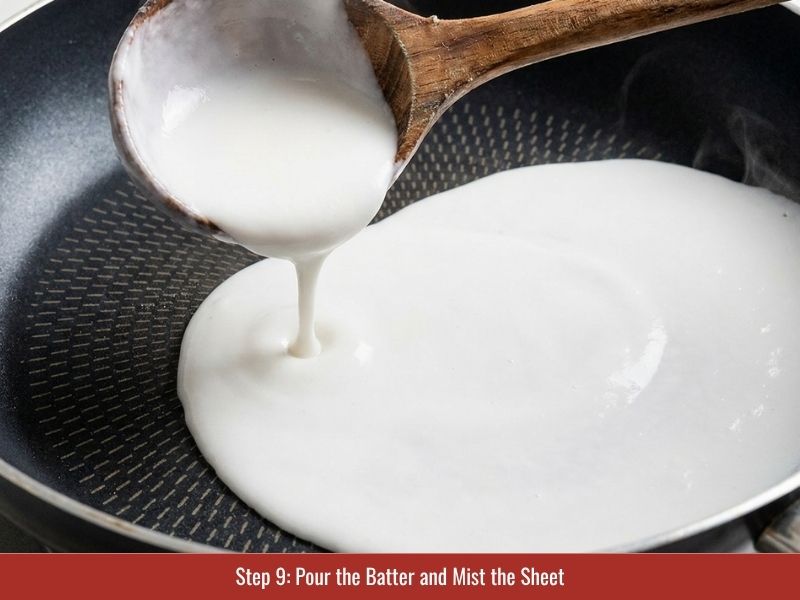 Spreading thin banh cuon batter across a heated skillet to create delicate rice sheets