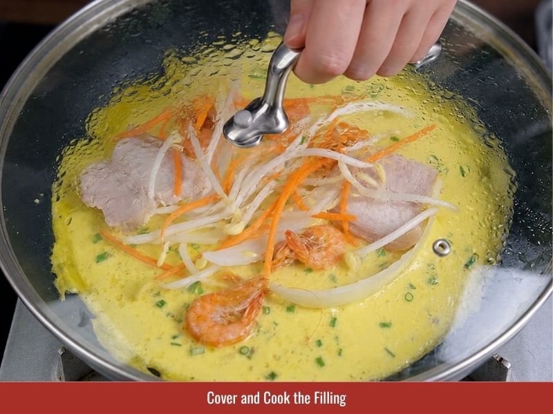Covering the skillet to cook the banh xeo filling while the batter sets