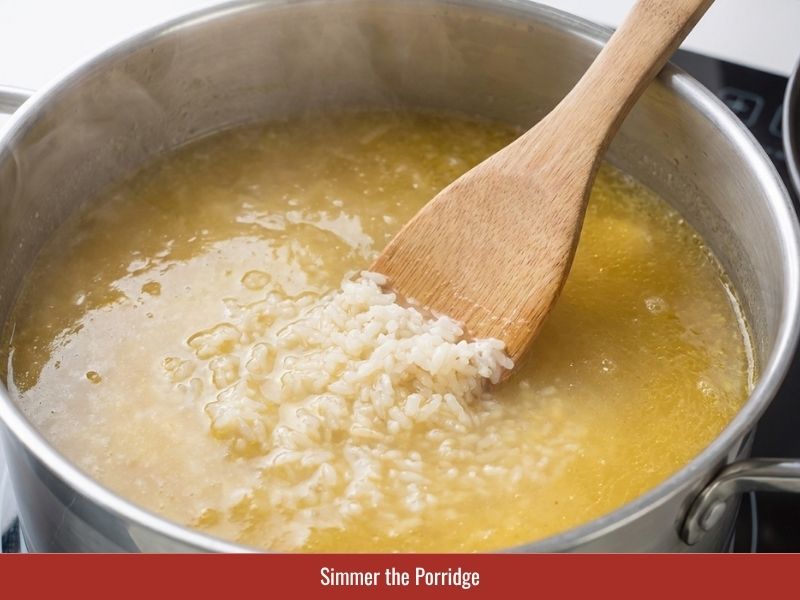Simmering toasted rice in chicken broth until the grains soften and bloom into porridge