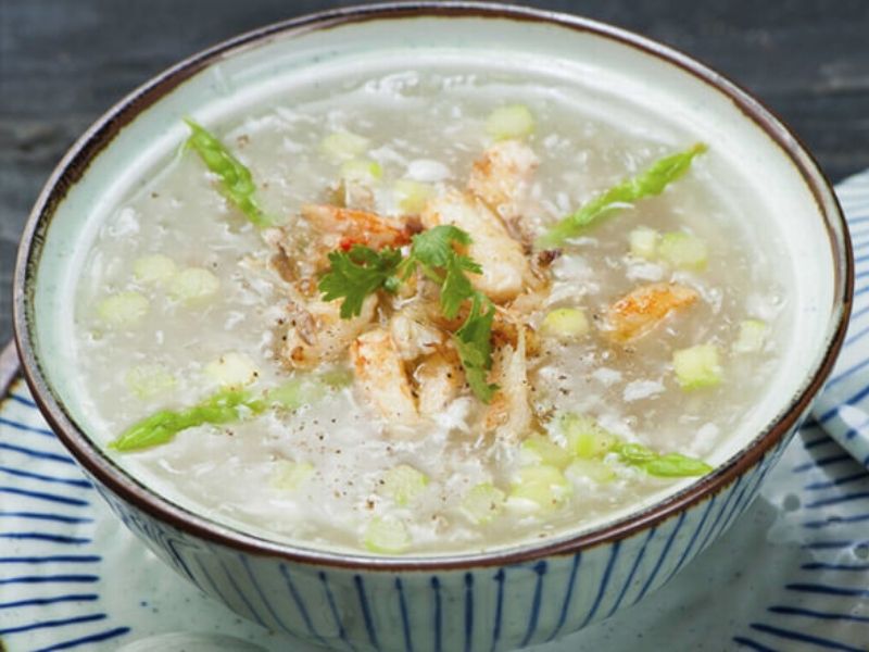Bowl of Vietnamese crab and asparagus soup with chicken, crab meat, quail eggs, corn, and smooth starch-thickened broth